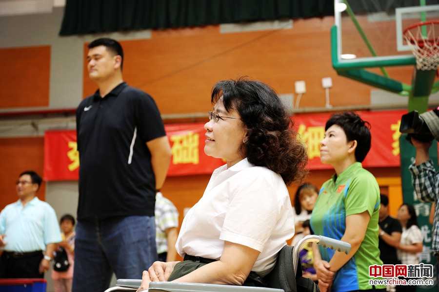 张海迪主席将篮球高高抛向空中为轮椅篮球赛开球，她和轮椅上的运动员们眼神都紧紧追随着那颗球，脸上绽放出期待又兴奋的笑容