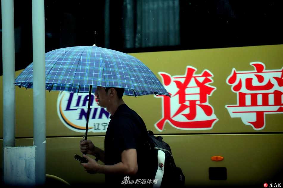 细密的雨丝中，周琦身披国家队的红色战袍，神情专注而坚定，步伐沉稳地走向训练馆，身後是同样冒雨前行的队友。