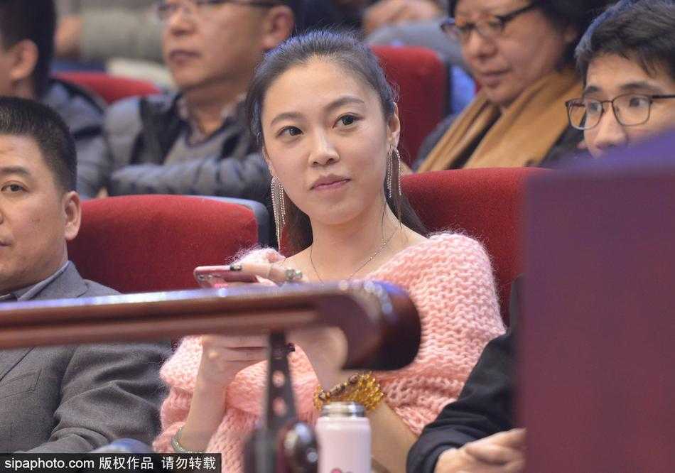 一位戴着黑框眼镜的知性美女球迷，脸颊上贴着山东队贴纸，她托腮凝望球场，眼神中充满了对主队取胜的渴望。