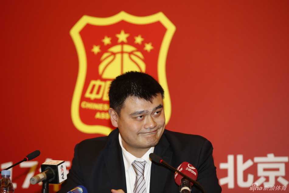 姚明在会场与人交谈时表情严肃，眉头微蹙，高大的身影在人群中格外醒目，举手投足间透露出领袖气质