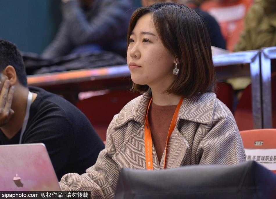 她一手握着手机，似乎想用镜头记录下此刻球场上的精彩瞬间，眼神中闪烁着对这份热爱之事的珍视，仿佛要将这份记忆永远珍藏。